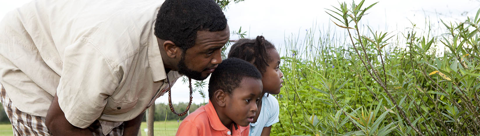 father and two children looking at plants
